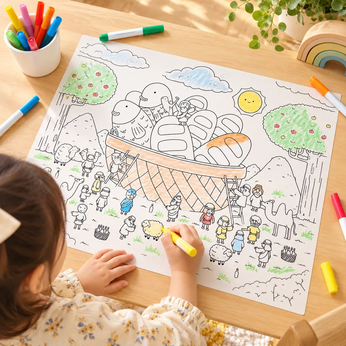 Child colouring Five Loaves and Two Fishes reusable silicone mat at wooden table