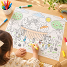 Child colouring Five Loaves and Two Fishes reusable silicone mat at wooden table