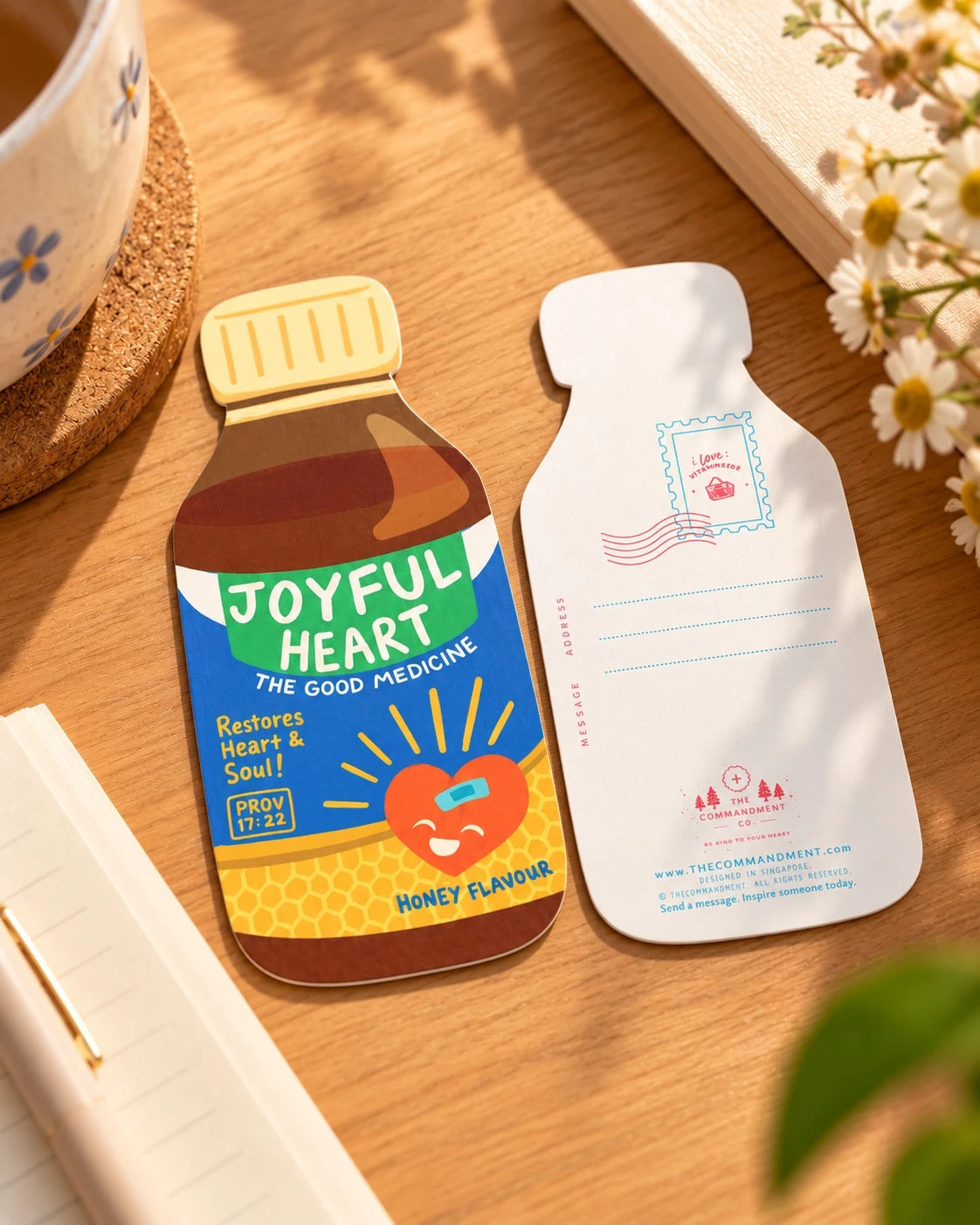 Joyful Heart Medicine LOVE SUPERMARKET card front and back displayed on a wooden desk beside a notebook