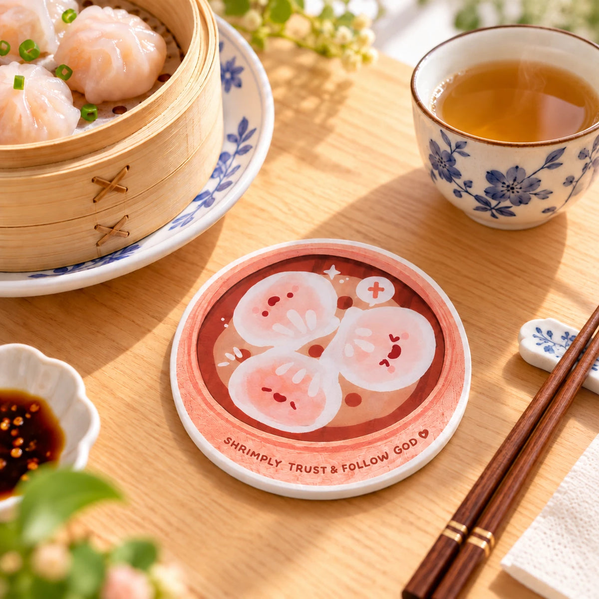 Shrimply Trust God illustrated Christian shrimp coaster on a wooden table beside dim sum and tea