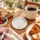 God is love and He loves me white round ceramic coaster displayed with coffee and breakfast pastries
