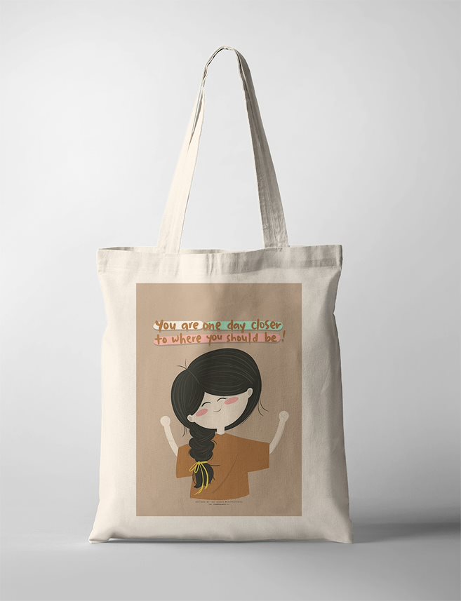 Illustrated faith based tote bag featuring a joyful girl with long braided black hair tied with a yellow ribbon, raising her arms in quiet triumph. The background is a warm beige, and the motivational quote reads, “You are one day closer to where you should be!” in a mix of handwritten fonts and uplifting colors. A charming Christian wall art piece that encourages perseverance and faith in God’s timing.

