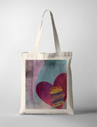 A tote bag with a bold, abstract design of a heart set against a textured purple and teal background. The heart features a layered C.S. Lewis quote: 'Though our feelings come and go, God's love for us does not.' A thoughtful modern Christian gift for all occasions.