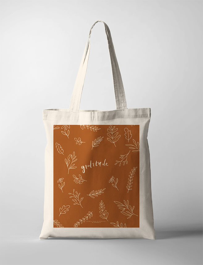 A faith-based gratitude tote bag featuring the word 'Gratitude' in elegant script, surrounded by autumn-colored leaves in warm tones.