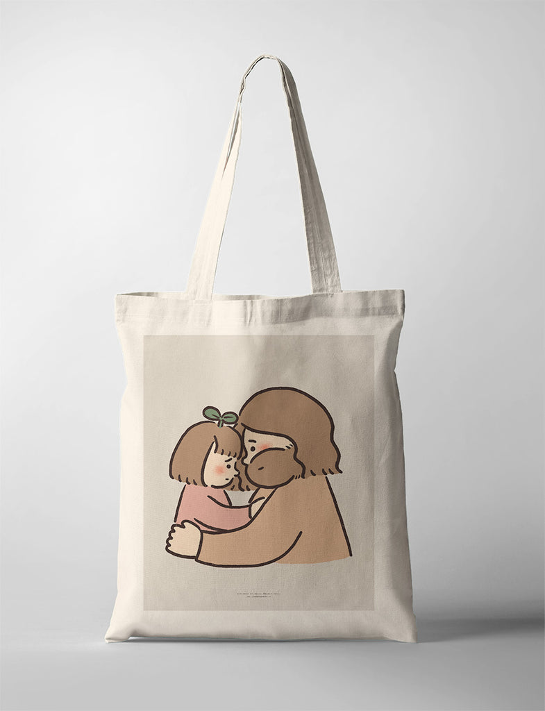 Canvas tote bag with a heartfelt illustration of Jesus sharing a tender forehead touch with a child, symbolizing comfort and love.