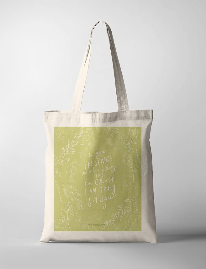 A Christian Tote Bag with a light green background and delicate white botanical illustrations surrounding a handwritten faith quote: 'In your presence is where I long to be. In Christ I am truly set free.' 