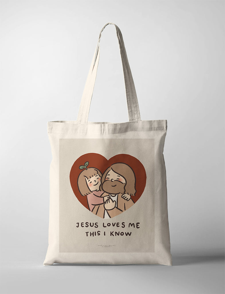 Canvas tote bag featuring a heartwarming illustration of Jesus embracing a joyful child, with the text 'Jesus Loves Me This I Know' as a message of love and faith.