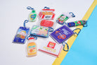 Complete Love Supermarket acrylic keychain collection displayed on a blue and yellow background, featuring ten playful faith-based designs.