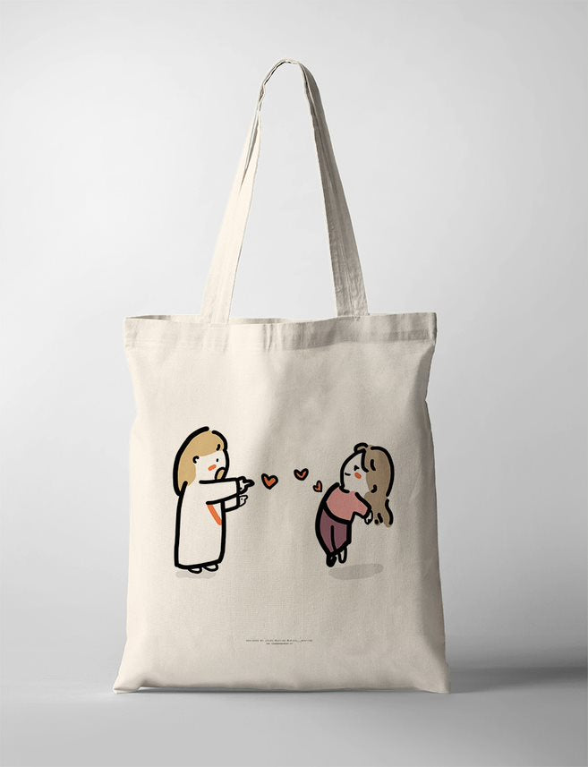 A delightful faith-based tote bag featuring an adorable illustration of Jesus playfully pointing at a joyful young woman, with floating hearts between them. This Christian tote bag beautifully represents God’s love and encouragement, making it a perfect piece for inspirational wall decor or a thoughtful faith-filled gift.