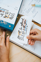  Hands tearing a page from The Project J Christian notepad featuring the inspiring verse "Do not be afraid, for I am with you" from Isaiah 41:10, perfect for uplifting daily planning and encouragement.