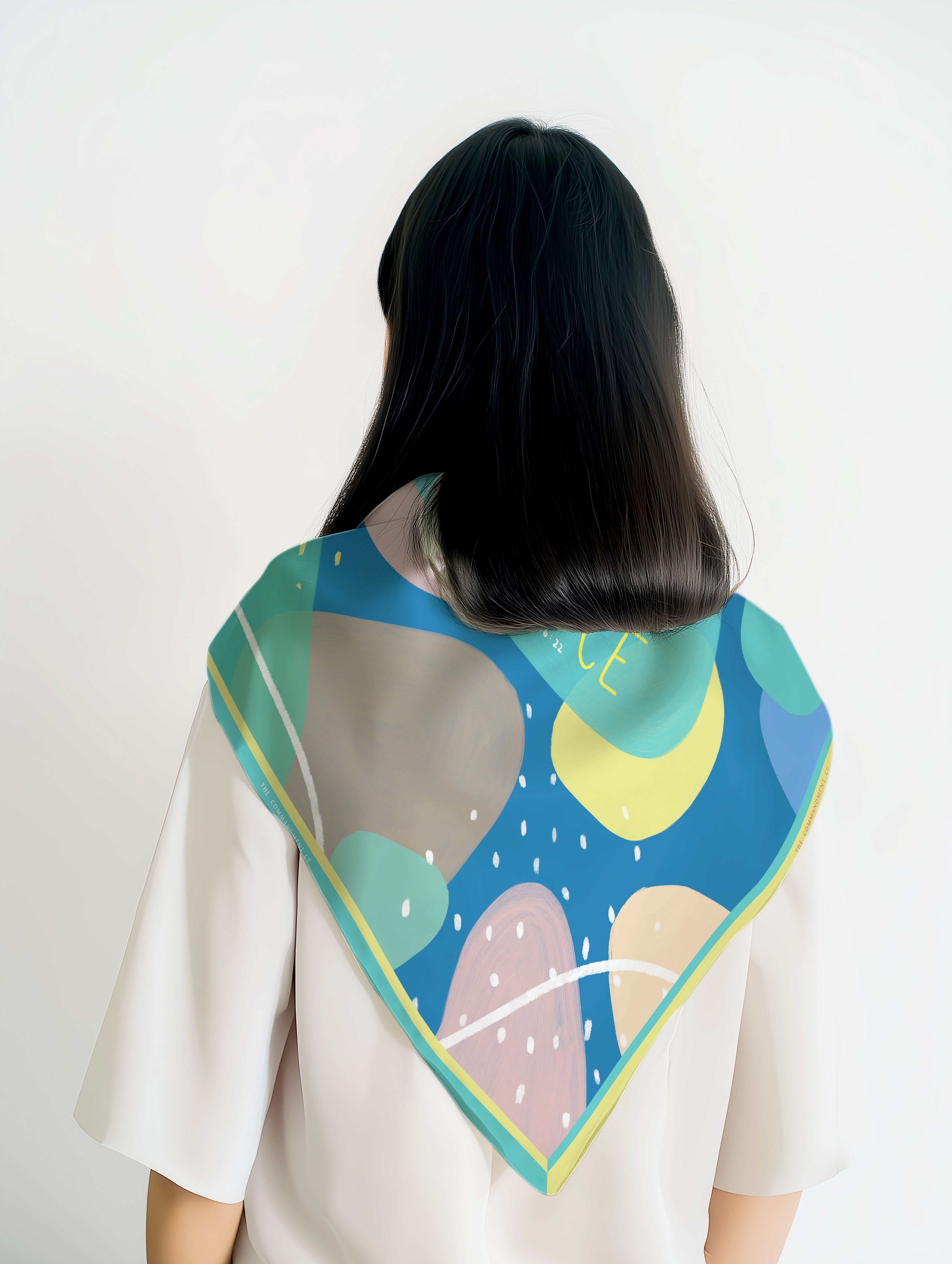 Abstract color-splashed scarf with teal border worn by a model from the back; a contemporary faith-inspired accessory by The Commandment Co