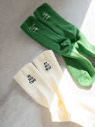 Cream and green ribbed-knit socks with embroidered messages—cream pair reads “IN HIS TIME” and “BY HIS WAY,” green pair reads “ALL THINGS NEW”—a faith-inspired accessory from The Commandment Co.
