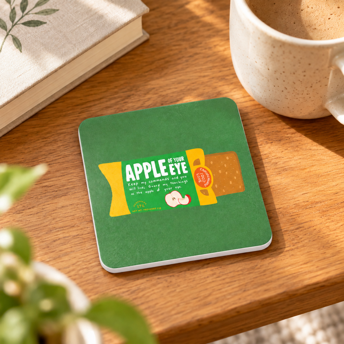 Apple of Your Pie LOVE SUPERMARKET Christian coaster beside a coffee cup on a sunlit wooden table.