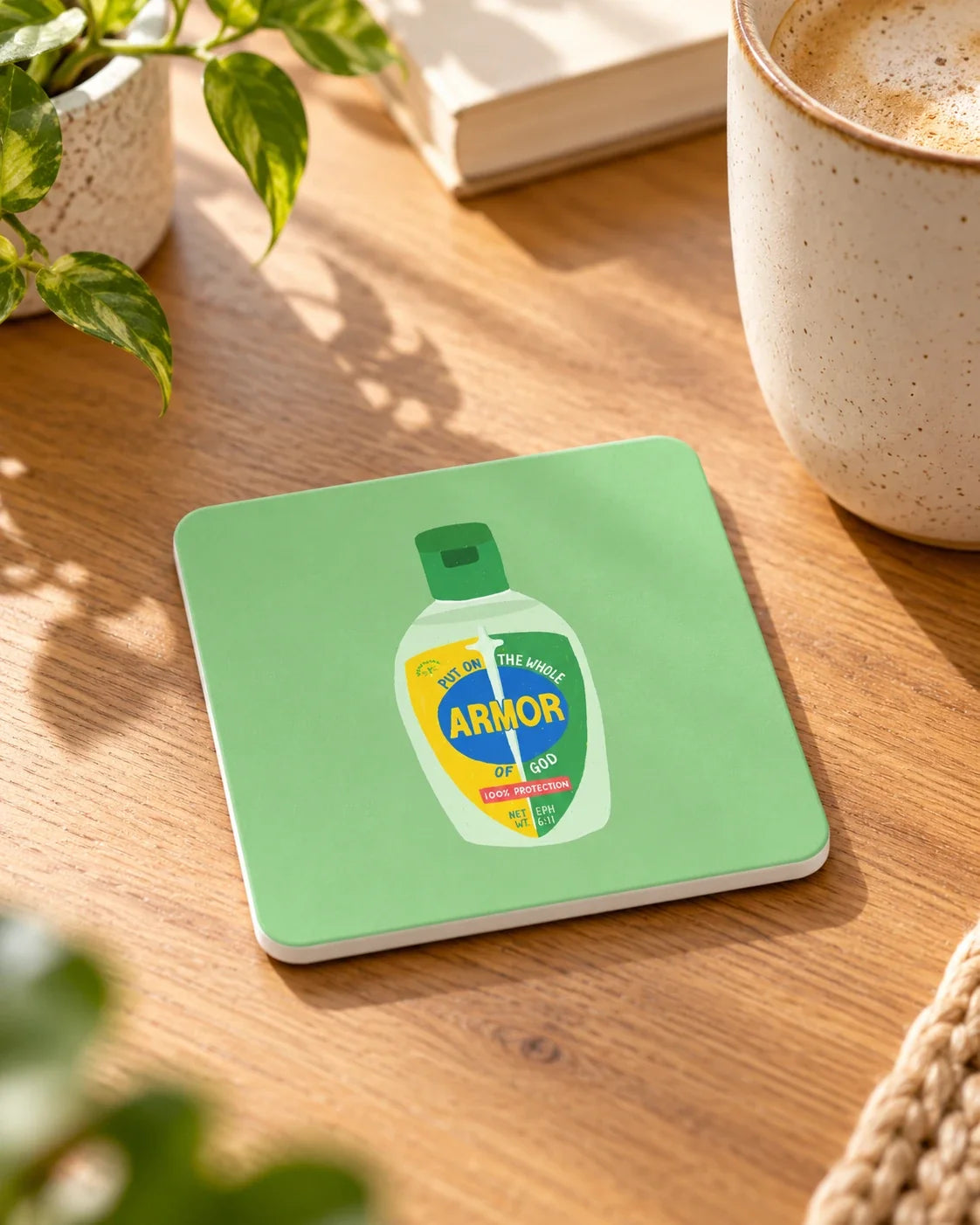 Armor of God sanitizer design coaster on wooden table beside coffee