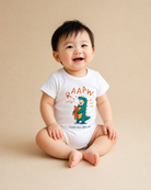 Baby wearing the RAAAW Come Now Little One dinosaur baby romper