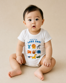 Baby wearing a white Welcome to the Love Zoo Christian romper with colourful animal illustrations
