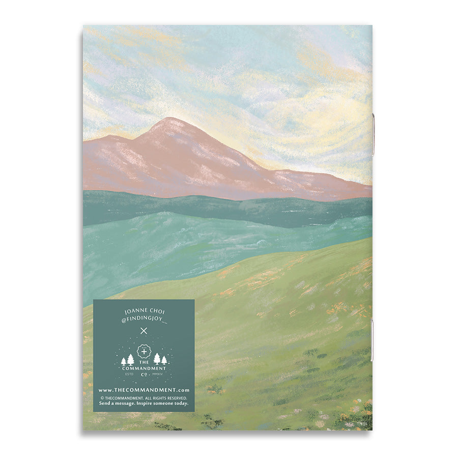 Back cover of a Christian-themed A6 notebook with a mountain illustration and branding details.