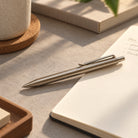 Classic brass ballpoint pen on an open notebook in warm natural sunlight