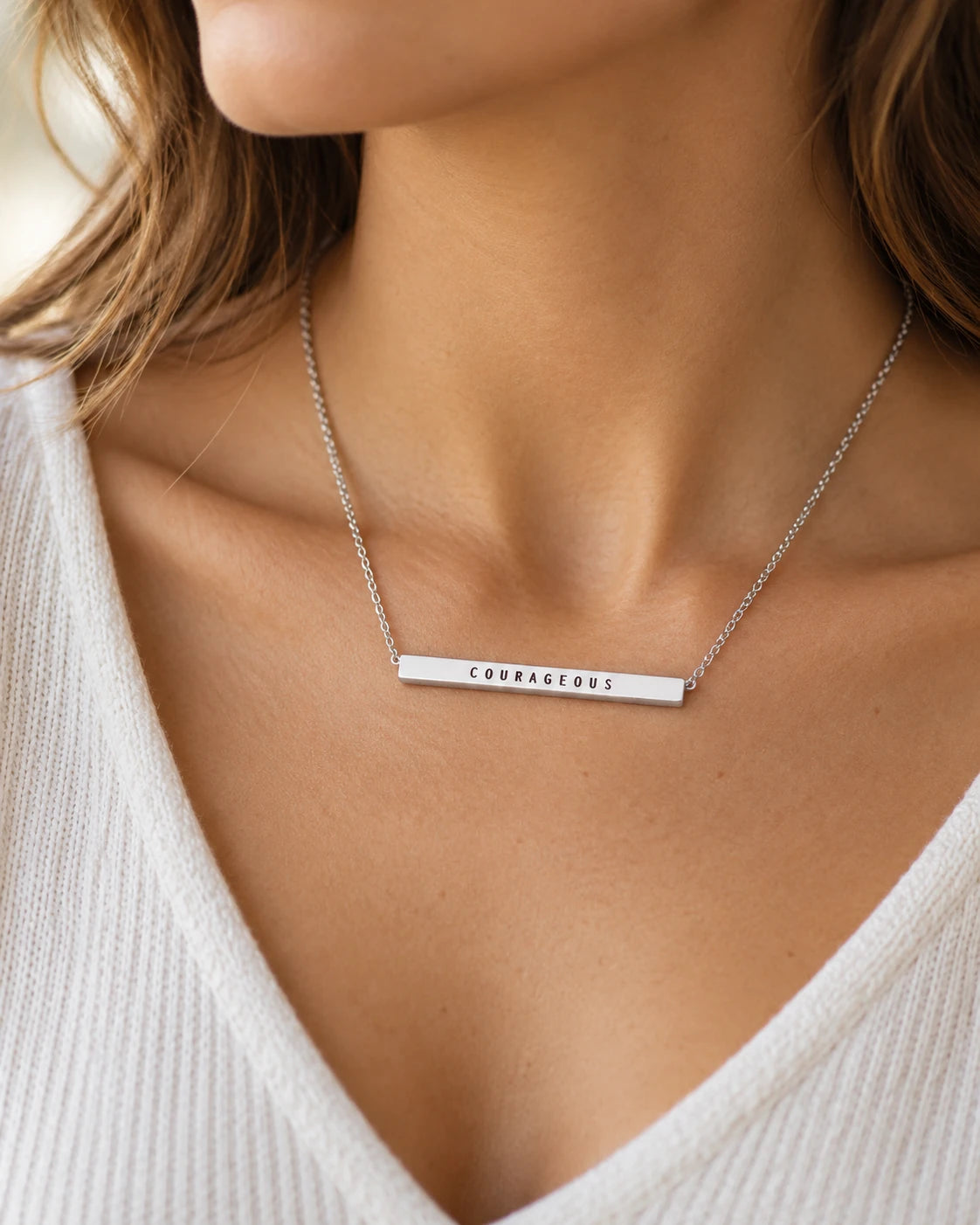 Silver Courageous bar pendant necklace worn with a cream knitted top in a close-up lifestyle photo