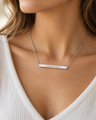 Silver Courageous bar pendant necklace worn with a cream knitted top in a close-up lifestyle photo
