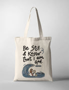 Cream canvas tote bag featuring “Be Still & Know That I Am God – Psalm 46:10” with illustrated wave and Jesus calming the storm design, Christian inspirational tote bag.