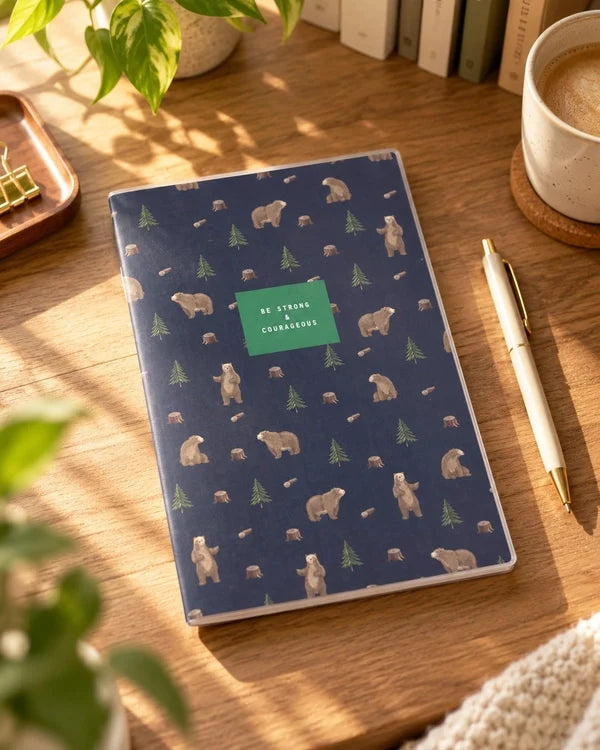 Be Strong and Courageous A5 notebook with bears and evergreen trees on a sunlit desk