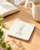 Be Strong and Take Heart coaster with colourful Psalm 27:14 lettering on a sunlit wooden table beside a book and mug