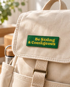 Be Strong & Courageous green embroidered Velcro tag on a beige backpack