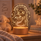 Beloved Child of God Shepherd Jesus night light glowing warmly on a bedside table.