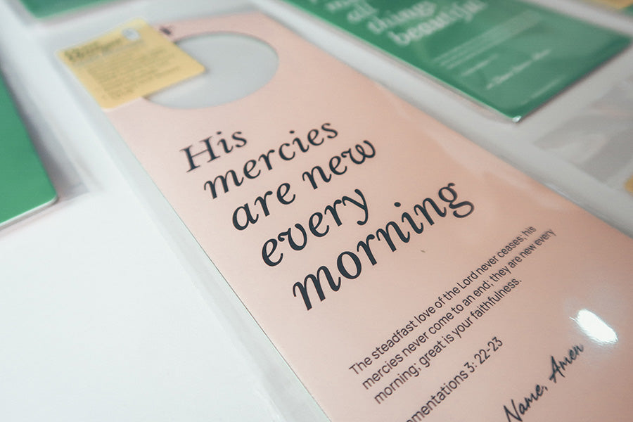 Close-up view of a pink Christian door hanger featuring the Bible verse 'His mercies are new every morning' from Lamentations 3:22-23, emphasizing faith and hope.