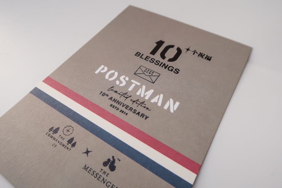 A detailed view of the "10 Blessings Postman" limited edition 10th-anniversary design, featuring bold typography, accent stripes in red, white, and blue, and logos from The Commandment Co. and The Messenger.