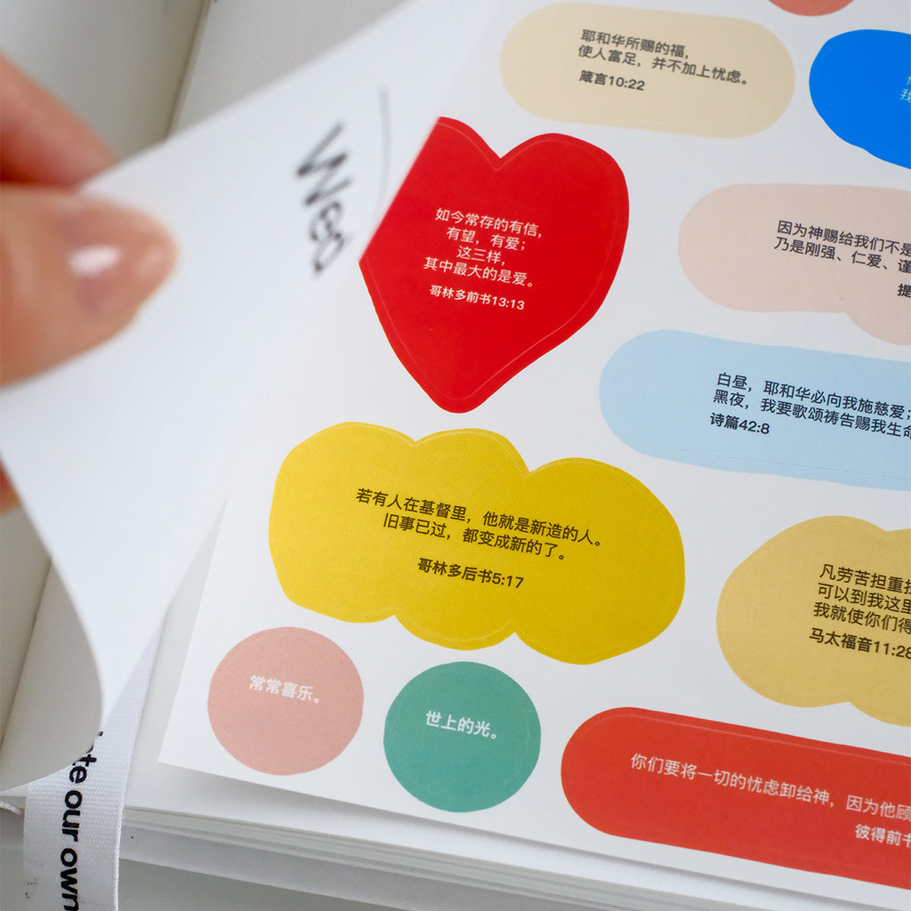 Close-up of a sticker sheet featuring colorful Bible verse designs, including a red heart and yellow cloud, for faith-based planner decoration