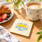Bless This Day Christian coaster styled on a sunlit breakfast table beside coffee and pastries.