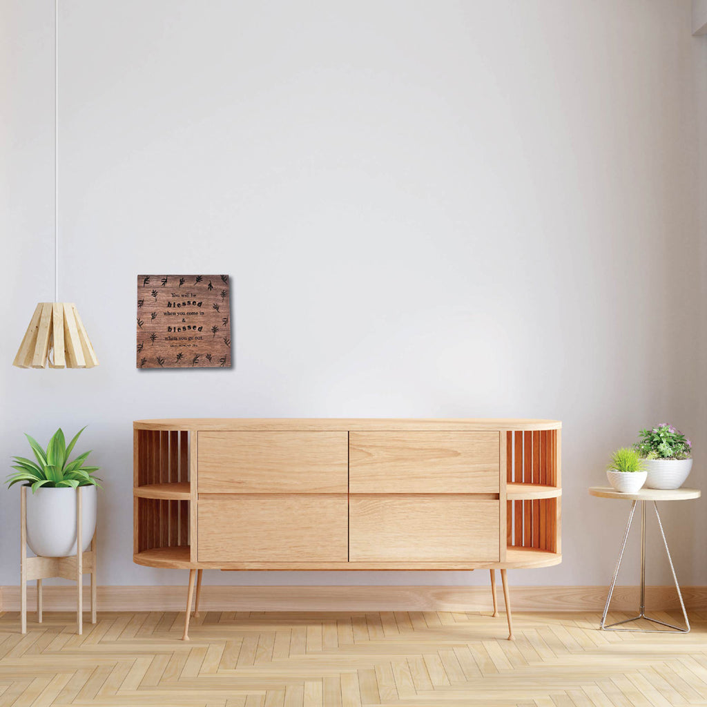 Minimalist room with a wooden board wall art featuring the scripture 'You will be blessed when you come in and blessed when you go out. Deuteronomy 28:6,' hung above a modern wooden console table