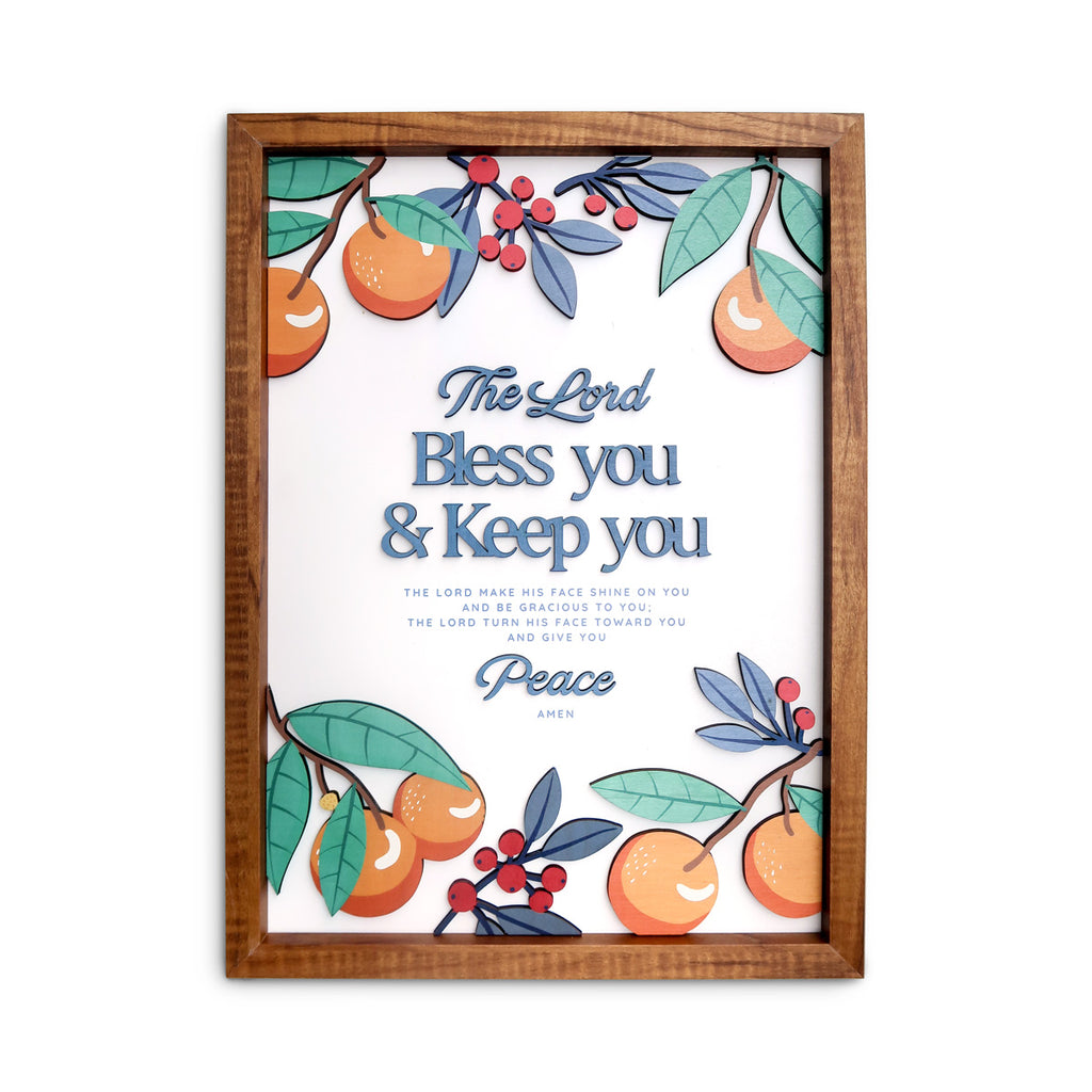 A wooden-framed wall art featuring the blessing "The Lord bless you and keep you," surrounded by vibrant orange fruits, green leaves, and red berries, designed as a Christian faith-inspired home decoration.