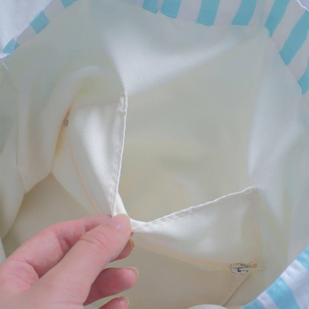 Close-up of a blue striped tote bag interior, showing a practical inner pocket for secure and organized storage.