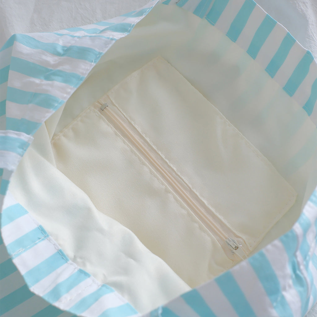 Interior view of a blue striped tote bag, featuring a zip pocket for practical and organized storage.