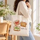 Bread of Life John 6:35 cream canvas tote bag with illustrated toast designs worn over the shoulder indoors.