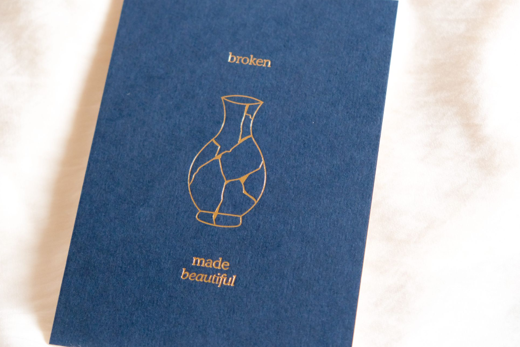 Minimalist letterpress art print with the words “broken” and “made beautiful” illustrated through a repaired ceramic vase.