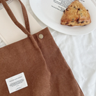 Close-up of a brown corduroy shoulder bag with an inspirational "God is like warm sunshine" patch, next to a plate with a scone and uplifting message, reflecting simple happiness and encouragement.