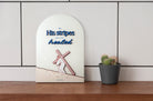 3D wooden Christian wall decor with the phrase 'By His stripes we are healed,' featuring an illustration of Jesus carrying the cross and the Bible verse Isaiah 53:5, displayed on a wooden shelf beside a potted cactus.
