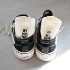 Cream ribbed-knit socks embroidered with "BY HIS WAY" and "IN HIS TIME" shown inside black sneakers — a faith-inspired accessory from The Commandment Co.