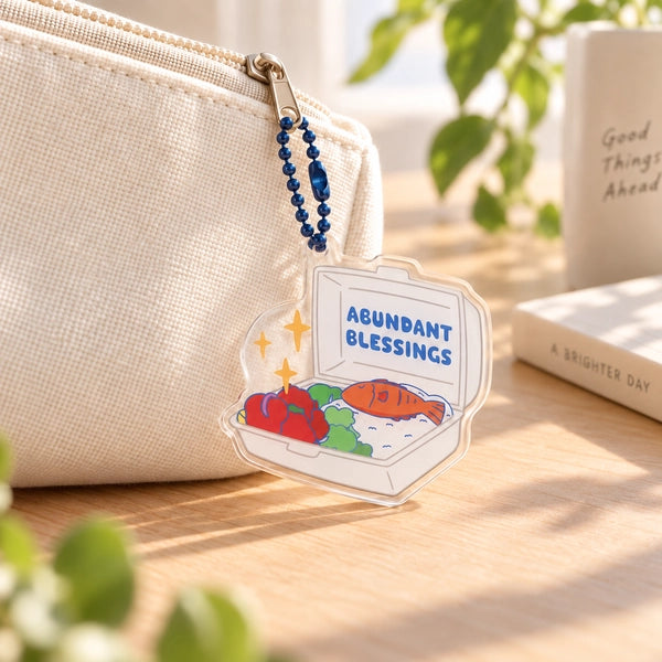 Cai Peng Abundant Blessings acrylic keychain hanging from a cream pouch in a bright lifestyle setting