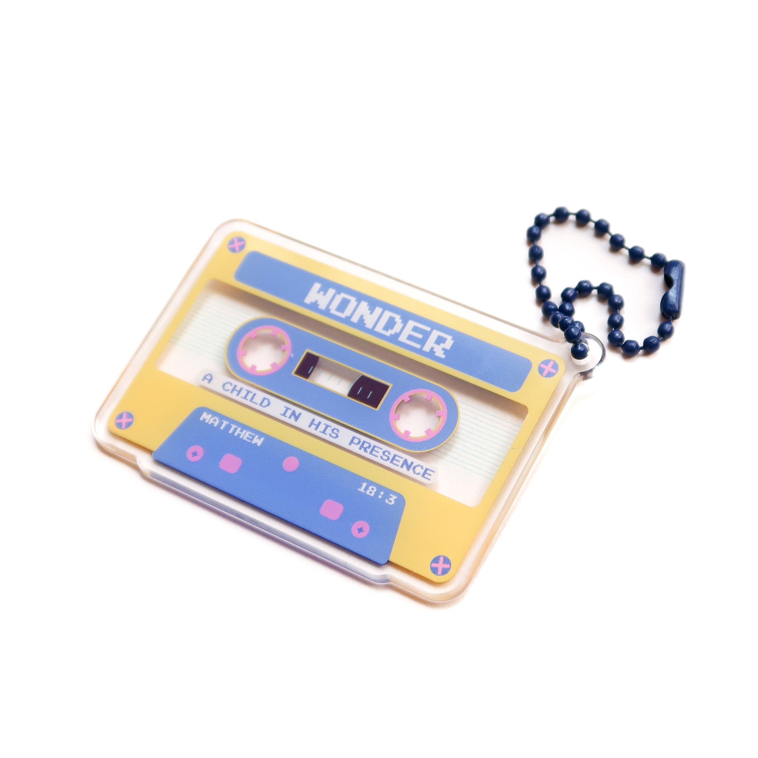 Acrylic cassette-tape keychain featuring the word “WONDER” on a yellow-blue cassette design, attached to a blue bead chain—a faith-inspired gift from The Commandment Co.