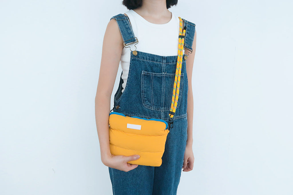 Yellow Pong Pong Bag worn casually over the shoulder, offering a lightweight, fluffy, and practical multipurpose storage option.