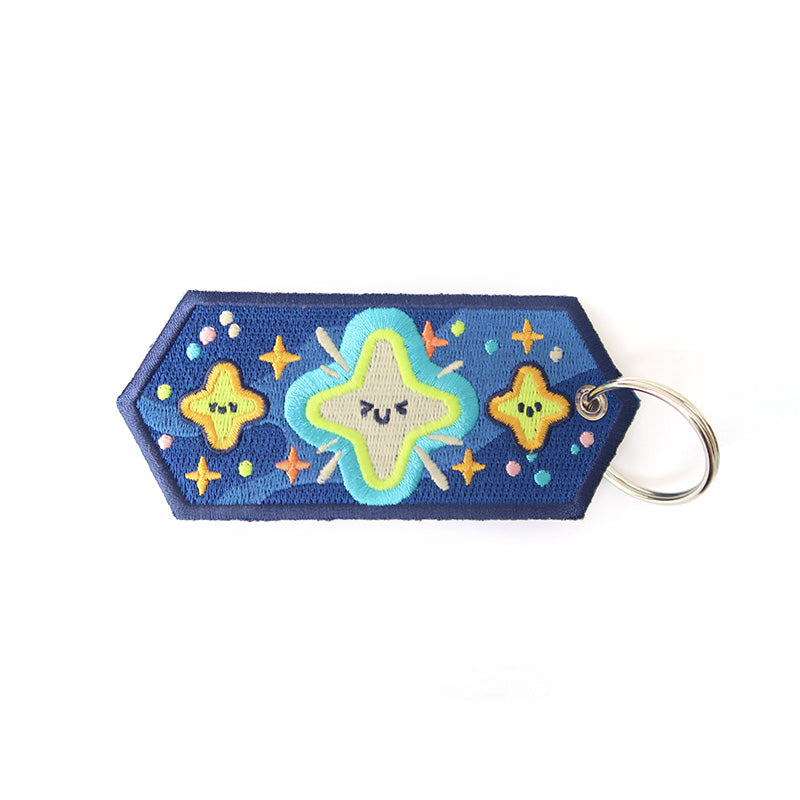 Inspirational keychain with colorful star embroidery on a blue background.