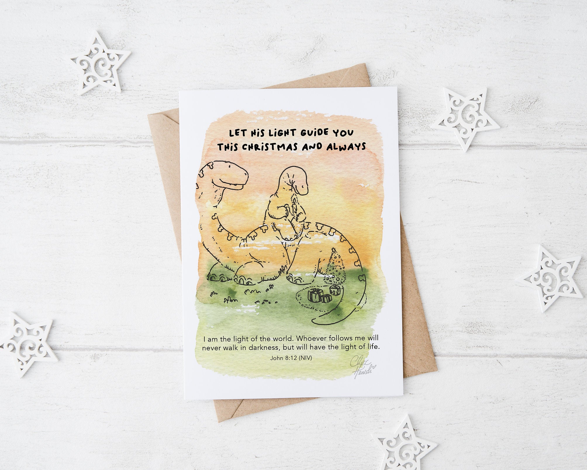 ChezHemdi A6 dino postcard with ‘Let His Light Guide You This Christmas and Always’ verse – Christian Christmas card from The Commandment Co