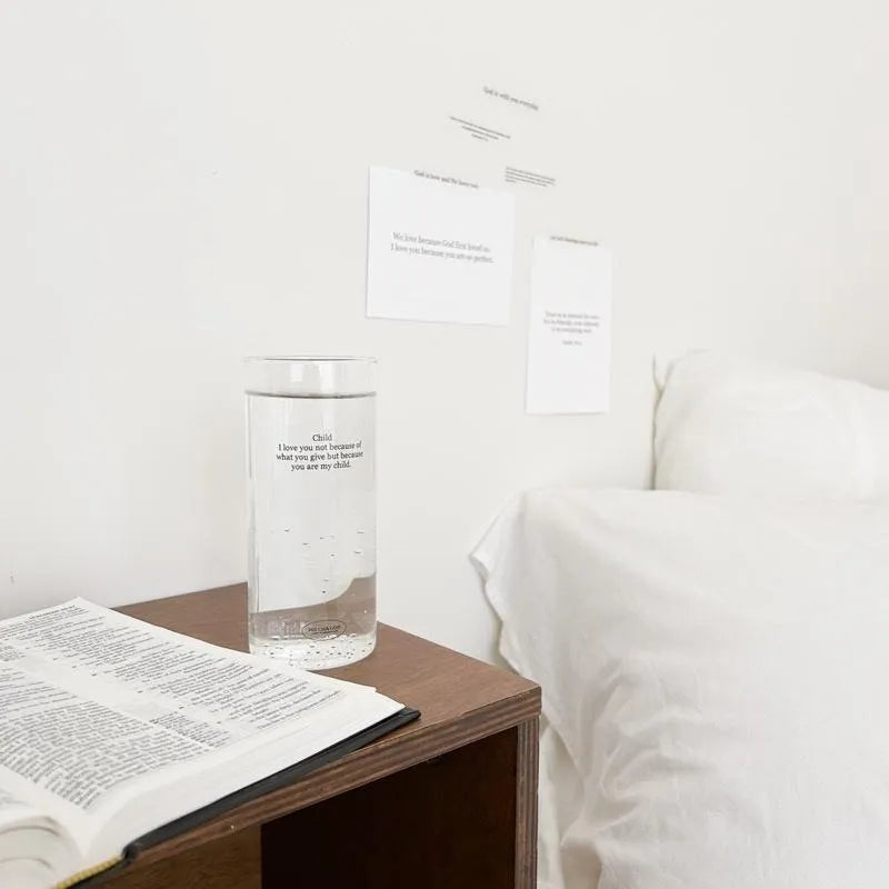 Child I Love You glass cup filled with water, placed on a bed-side table next to an opened Bible