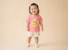 Child wearing the pink Be Strong Milk kids T-shirt in a warm studio setting