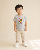 Young child wearing the grey Blast Off rocket kids T-shirt with beige trousers